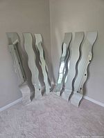 Six wavy edge full-length mirrors standing against wall