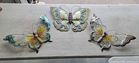All three metal butterfly wall ornaments on table