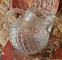 Full view of clear ball-form waffle-pattern pitcher on chair