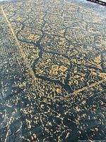 Angled close-up showing pile texture and distressed gold pattern on black background