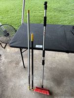 Two telescopic poles and push broom standing for size reference