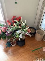 Assorted silk flower arrangements in various vases and planters on floor