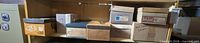 Eight various cardboard boxes on a shelf containing assorted postcards