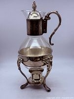 Full view of glass carafe assembled on ornate silver-plated stand