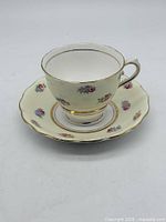 Teacup on saucer front view showing pattern and gold trim