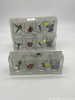 Two sealed packs each containing six insect-themed shot glasses