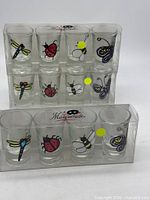 Two unopened packs each containing six Masquerade insect-designed shot glasses