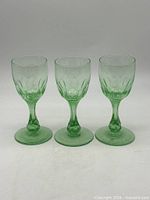 Front view of three green uranium glass stemmed glasses