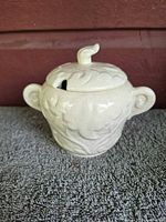 Front view of cream ceramic jam pot with lid showing relief design and handles