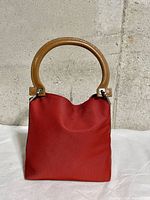 Front view of red canvas clutch with brown leather circular handle