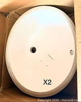 Top view of white oval sink in original box, showing faucet hole and overflow