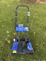 Front view of Snow Joe snow blower showing LED headlight, battery compartment, discharge chute, wheels, and handle