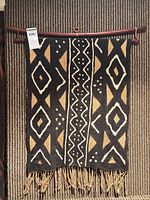 Front view of geometric cotton tapestry with fringe on wood rod