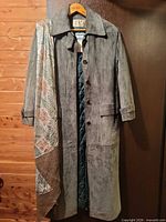 Front view of gray charcoal suede trench coat on hanger showing full length, button front, and patterned lining