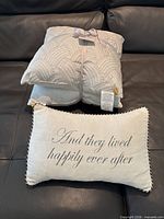 Pair of DozzZ pillows, one on top of the other with retail ribbon and tag visible
