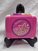 Front view showing Barbie branding, star graphic window and pink casing
