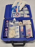 Open blue plastic first aid kit showing full contents in organized compartments