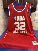 Front view of red NBA 32 All-Star jersey with logo, lettering and bottom patch visible