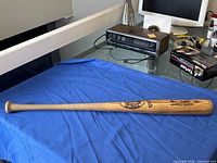 Full view of wooden Louisville Slugger bat on blue cloth