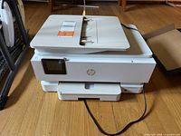Front view of white HP ENVY Inspire printer with power cord visible