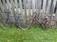 Both bicycles leaned against wooden fence showing full side profiles