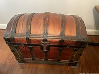 Full view of domed wooden trunk with metal straps and hardware