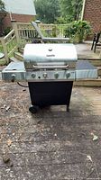 Full view of Char-Broil 4-burner propane grill showing stainless lid, control panel, side shelves, wheels