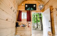 Interior cabin view with TV, coffee station, hooks and open door to spa grounds