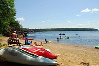 Kayaks on sandy beach beside lake, showing onsite recreation
