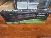 Front of boxed portable barbecue grill showing product image and branding