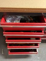 Open red drawers showing multiple coiled extension cords and bag of hardware