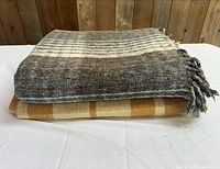 Two folded plaid wool blankets stacked, showing color and thickness