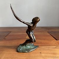 Front view of bronze metamorphosis sculpture showing kneeling winged figure on base