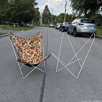 pair of butterfly chairs on street showing one with floral sling and one frame only