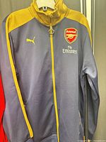 Full front view of the navy and gold Puma Arsenal track jacket hanging