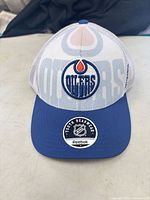 Three-quarter front view showing cap, visor, mesh crown and Oilers logo