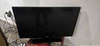 Front view of Samsung 32-inch television on stand with remote visible