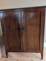 Front view of wooden cabinet with two doors and knobs