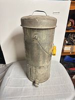 Full view of galvanized cylindrical water cooler showing lid, handle, spigot