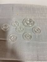 All seven clear glass floating flower rings laid out on fabric surface