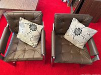 Top view of both brown faux leather lounge chairs with pillows