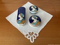 three lidded boxes on white doily top view showing portrait lids