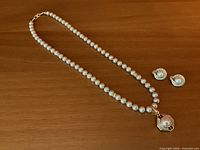 Front view of pearl necklace with pendant and pair of clip-on earrings