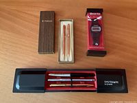 Overview of all items: watch in box, Parker pen-pencil set in box, Systemark case with three pens