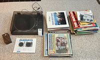 Overall lot showing turntable, power cable, manual and two stacks of records