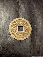 Obverse of brass token showing Mandarin name, snakes, 1979 date