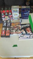 Full lot overview on table with bottles, boxes, books, mini Stanley Cup