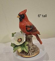 front view of ceramic cardinal on stump with flower