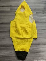 Front view of yellow banana costume laid flat showing shape and black tip