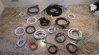 All 25 coiled Ethernet cables spread on countertop, showing color and length variety